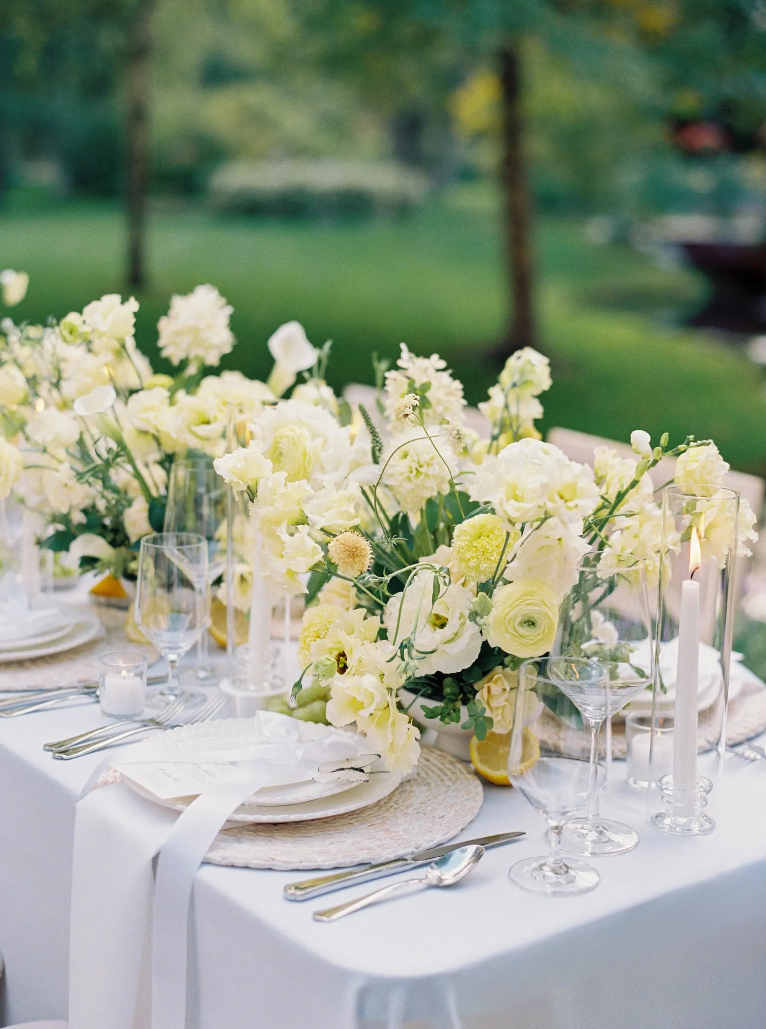 Oceana's Gardens outdoor dining table with white and cream floral centerpiece and candles