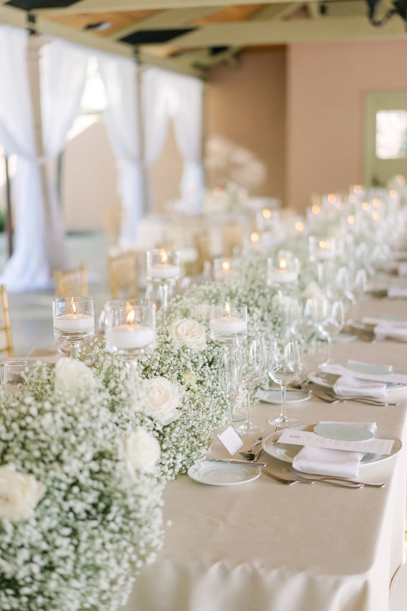 Wedding reception table with white flowers, candles, and place settings