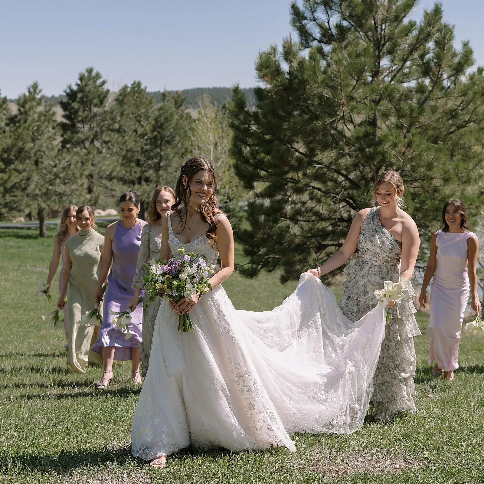 Bride and bridesmaids in pastel dresses at outdoor mountain park