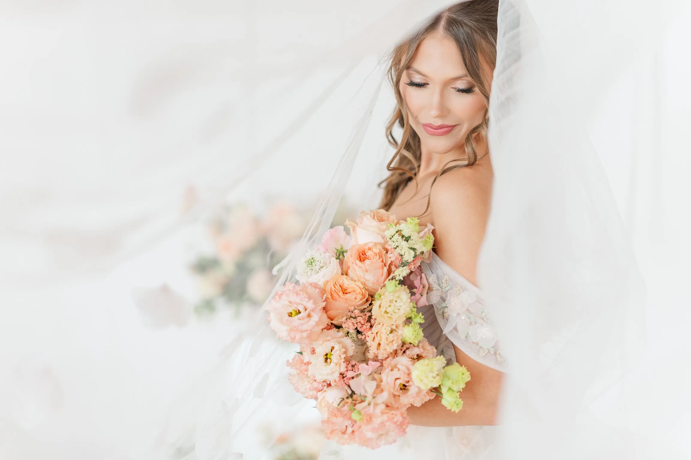 Bride in lace wedding dress with pink and peach bouquet