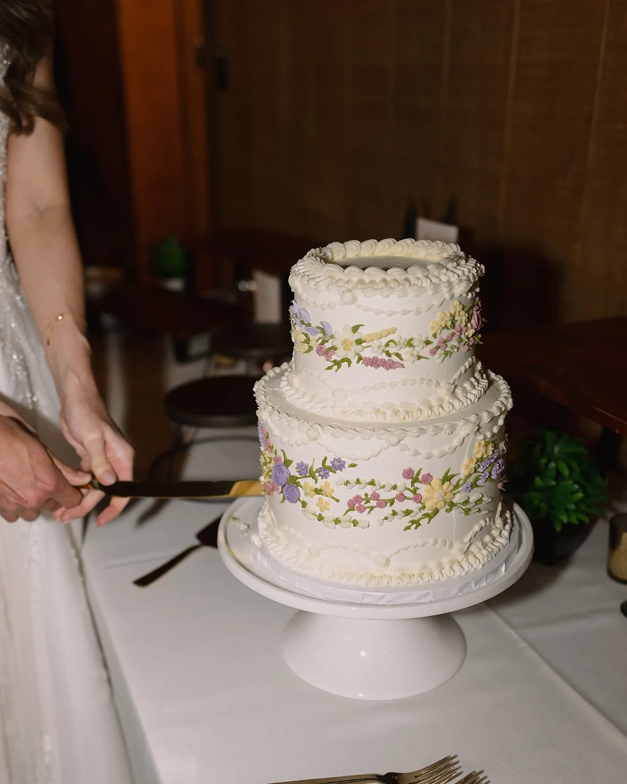 Three-tier white wedding cake with pastel floral piping
