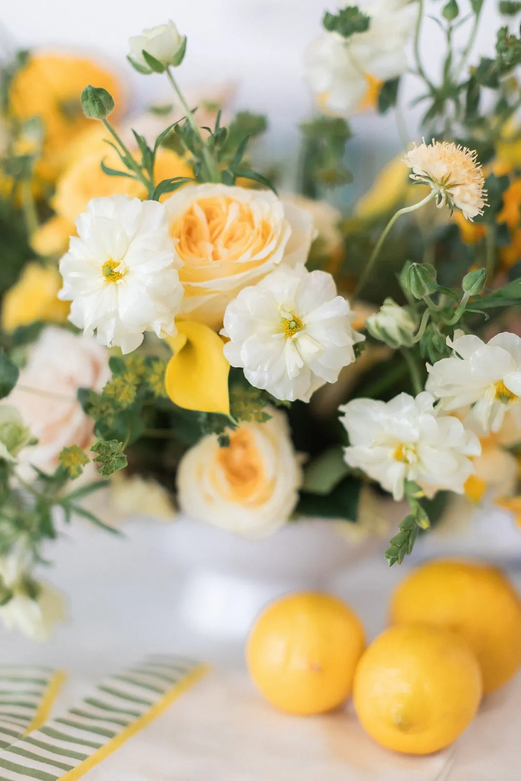 White, yellow, and peach floral arrangement with lemons
