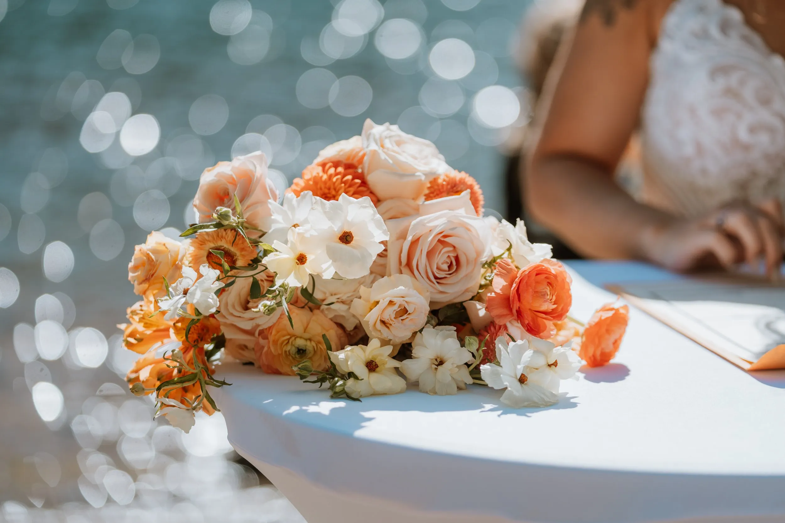 Woods and lake wedding with peach, white, and orange bouquet waterside